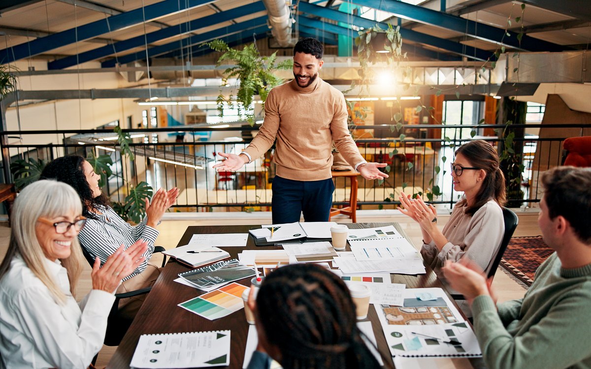 Marketing team reviewing brand layouts and color palettes around a table in a loft office