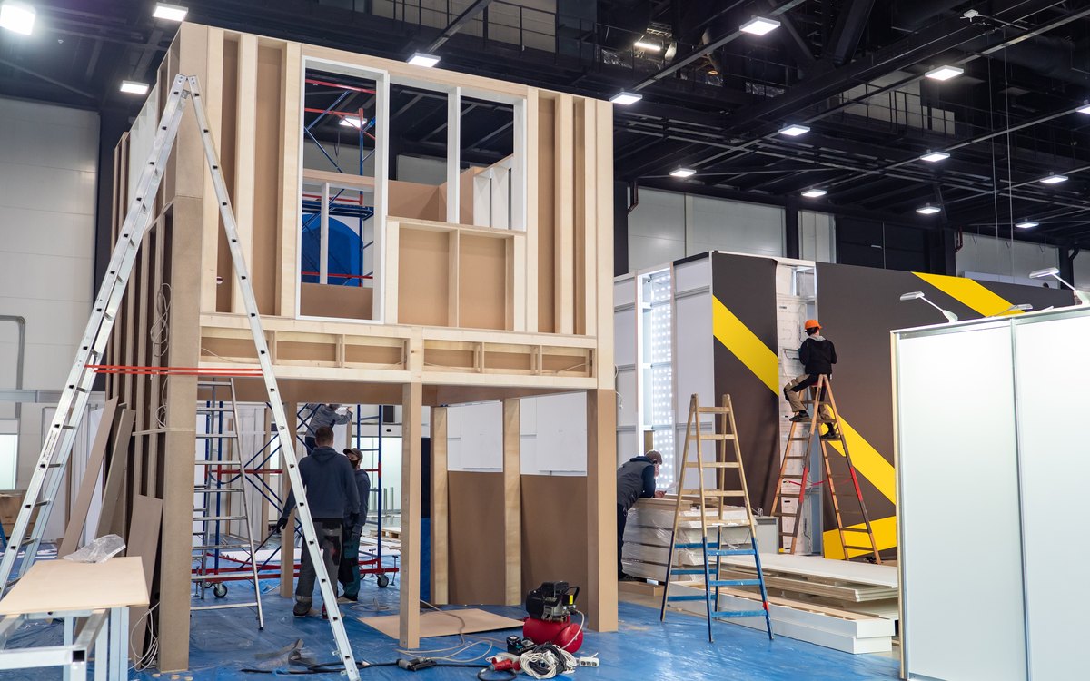 Crew assembling a custom two-story trade show booth on an exhibition floor