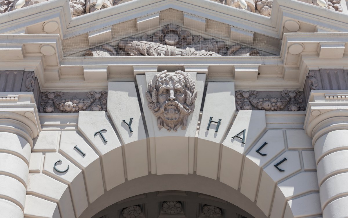 Carved stone City Hall lettering above a municipal building entrance arch